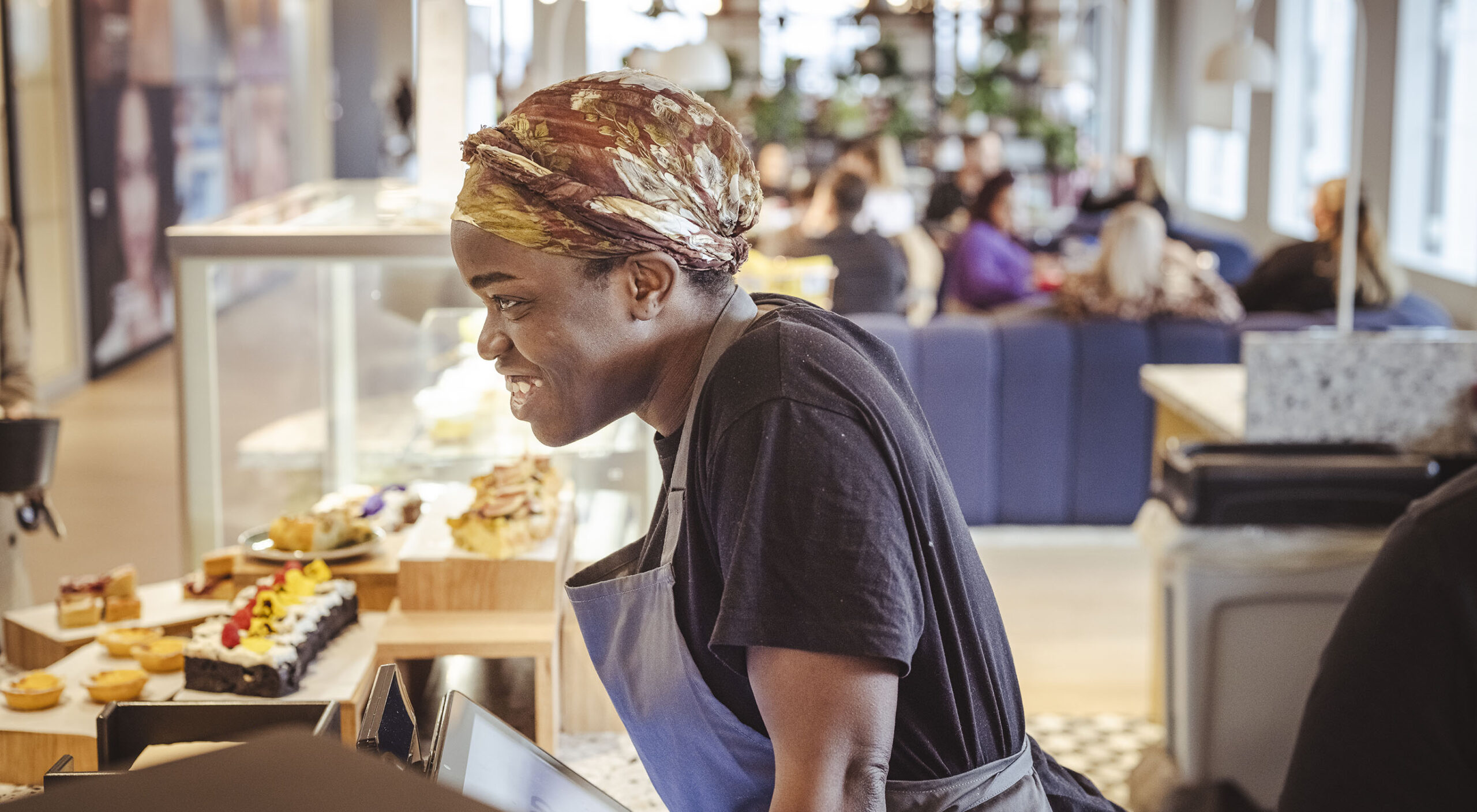 Barista leaning over a counter full of cakes