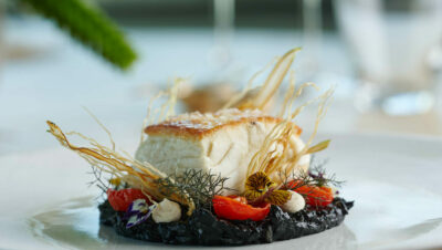 Fine dining savoury course on a plate with dining room background